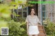 a woman standing in front of a house wearing a white skirt