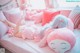 A woman laying on a bed with a pink stuffed animal.