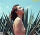 A naked woman standing in front of a palm tree.