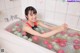 A woman sitting in a bathtub filled with water balloons.