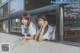 A couple of young women sitting next to each other near a window.