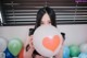 A woman holding a large white balloon with a red heart on it.