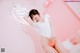 A woman in a white shirt and orange panties posing on a bed.