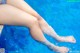 A woman's legs in a swimming pool with water droplets.