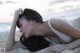 A woman in a white bikini laying on the beach.