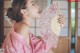 A woman in a pink kimono holding a fan.