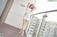 A woman in a white top and skirt posing on a balcony.