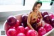 A naked woman sitting in a bathtub filled with pink balloons.