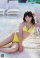 A woman in a yellow bikini laying on the sand.